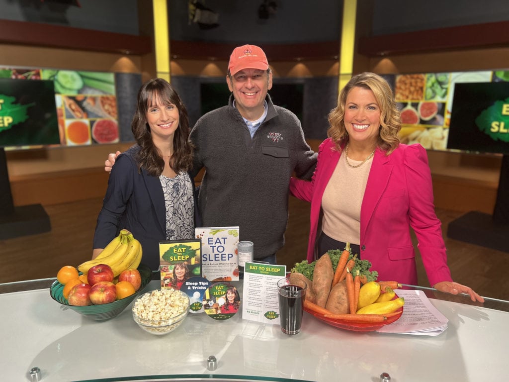 3 individuals on TV set with table of healthy food