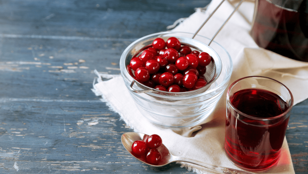 tart cherry juice in a glass and bowl of tart cherries